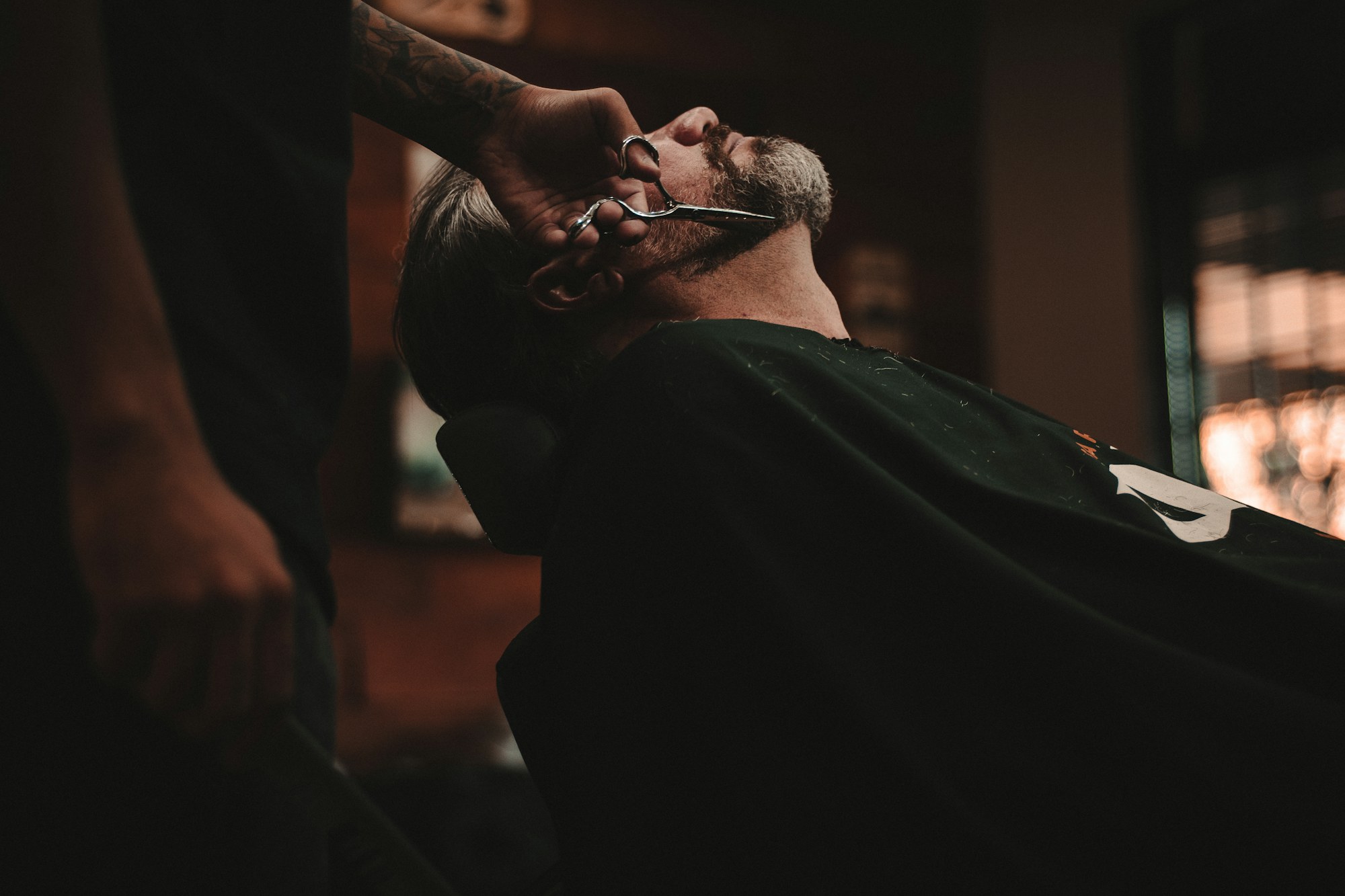 A barber at NOIR Barber Studio trimming a client's beard with precision scissors